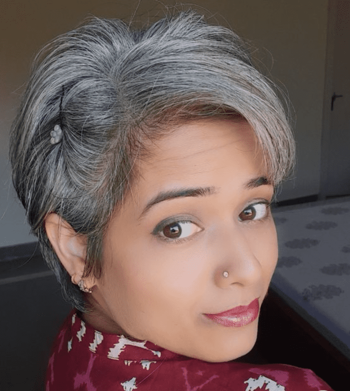 a woman with a gray hair pixie cut turns to the camera