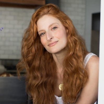 a woman with long red hair smiles at the camera