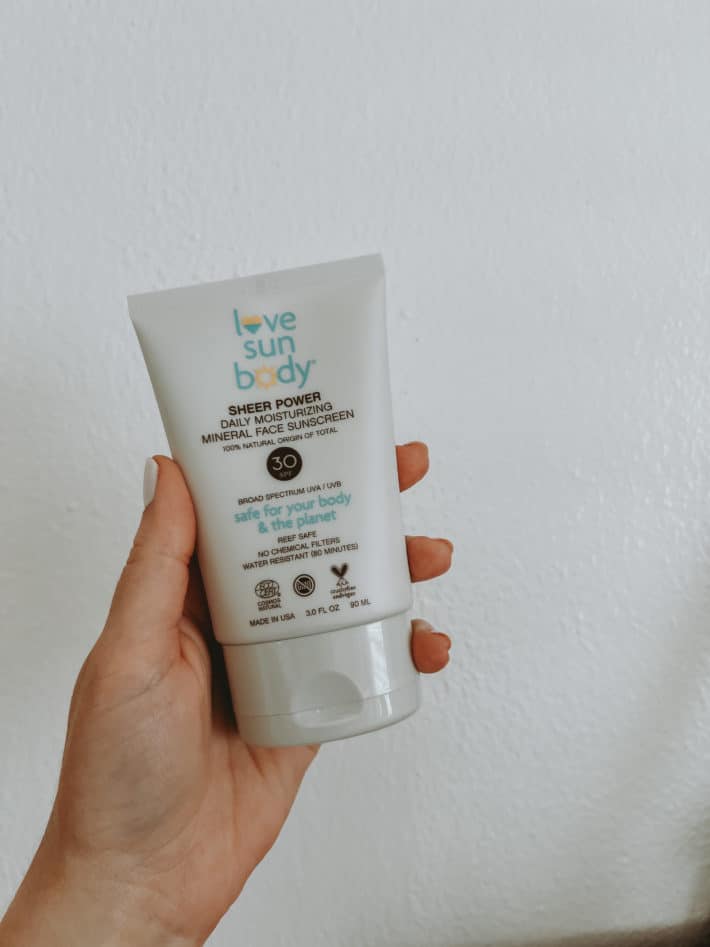 a bottle of love sun body spf is being held in a hand