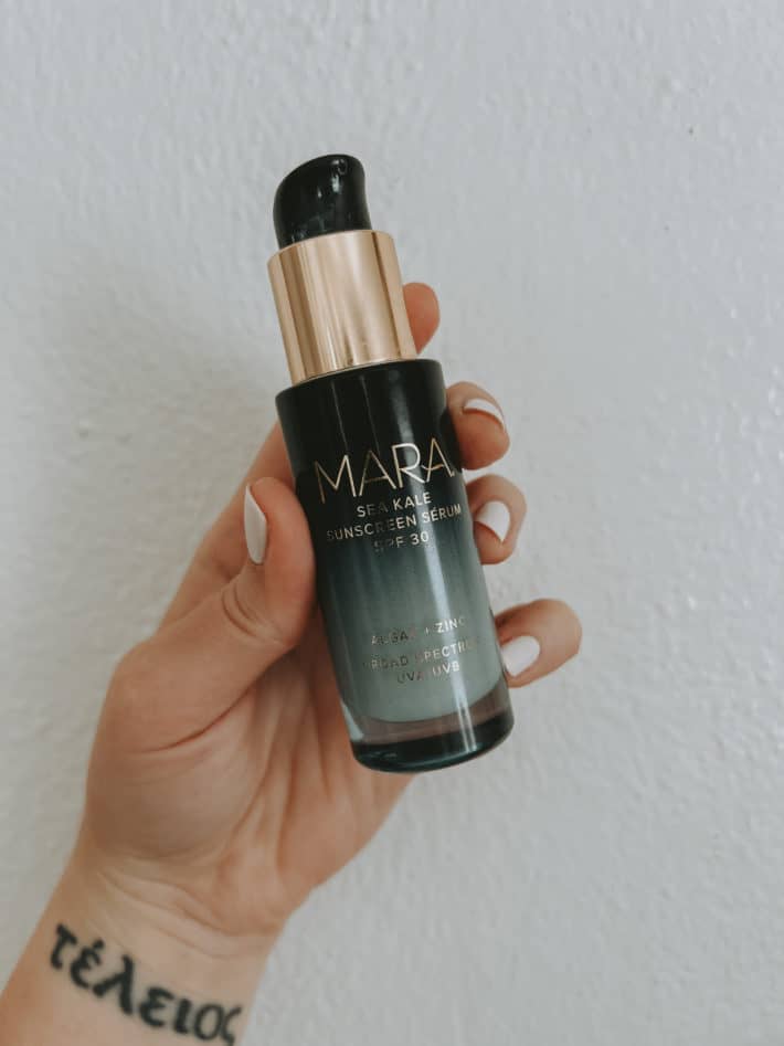 a container of mara sea kale sunscreen serum is held in a hand