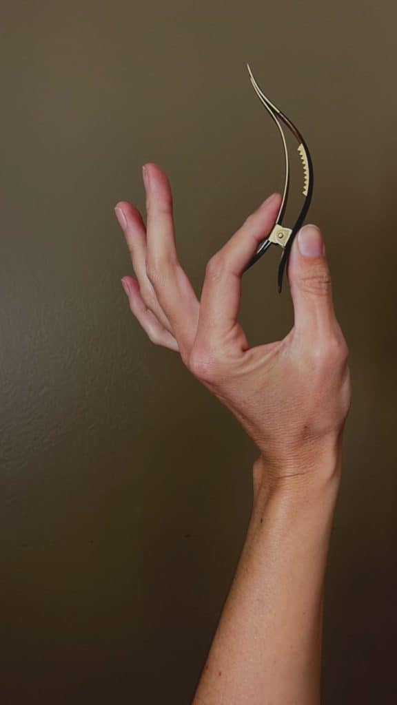 a ficcare hair clip is pinched between a persons finger and thumb