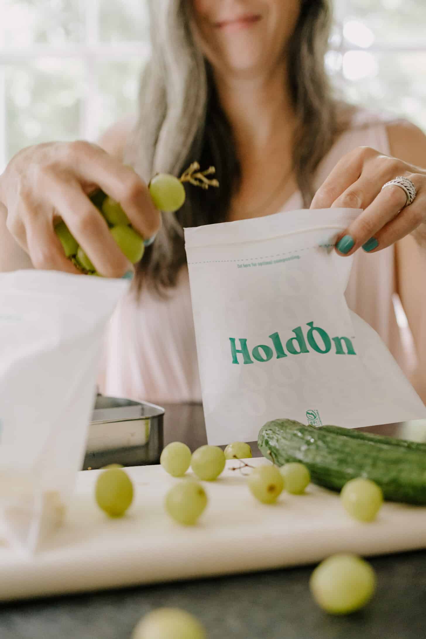 a woman fills a HoldOn compostable baggie with grapes