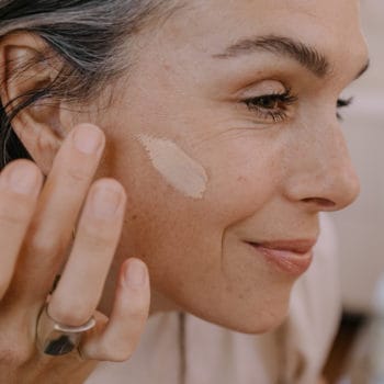 a woman wipes tinted face spf on her cheek