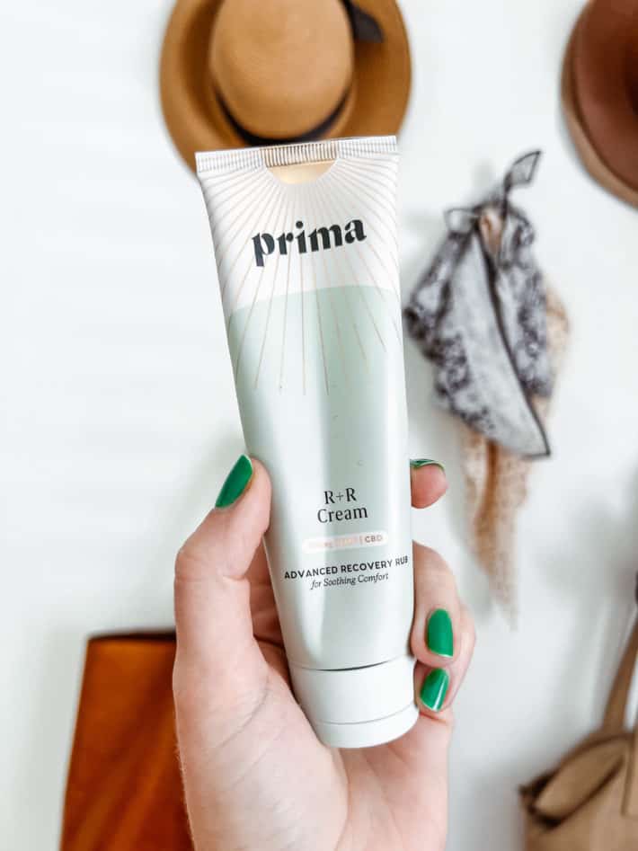 a tube of Prima R + R cream is held in a hand with painted green fingernails