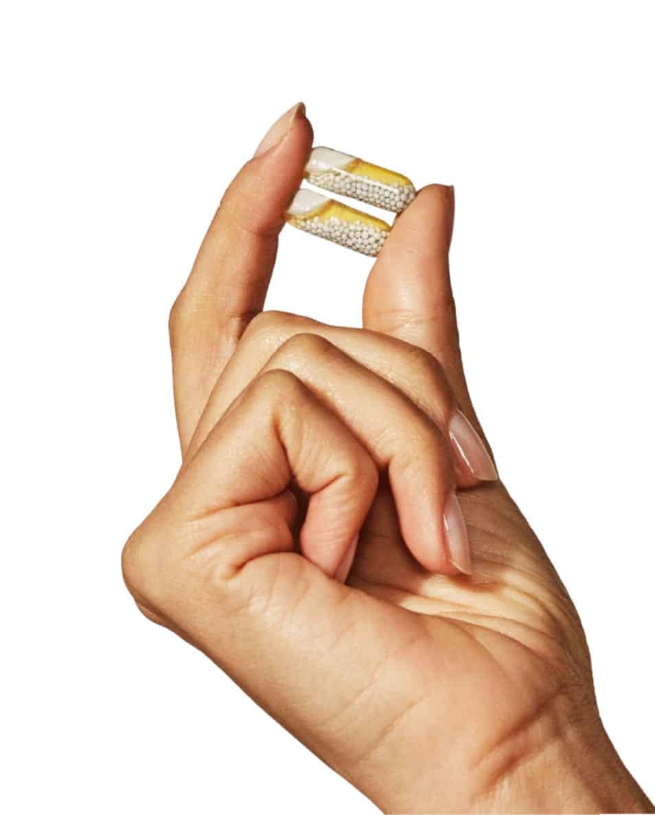 a hand holding a capsule of ritual brand women's daily vitamin