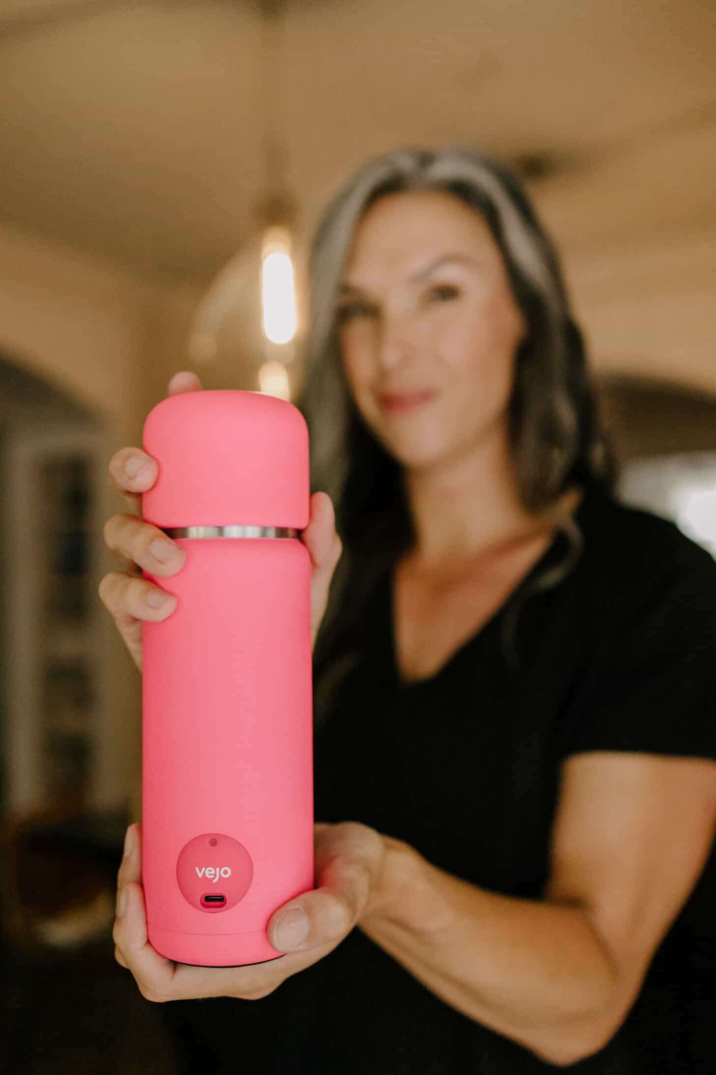 a woman in the background holds up a hot pink portable blender