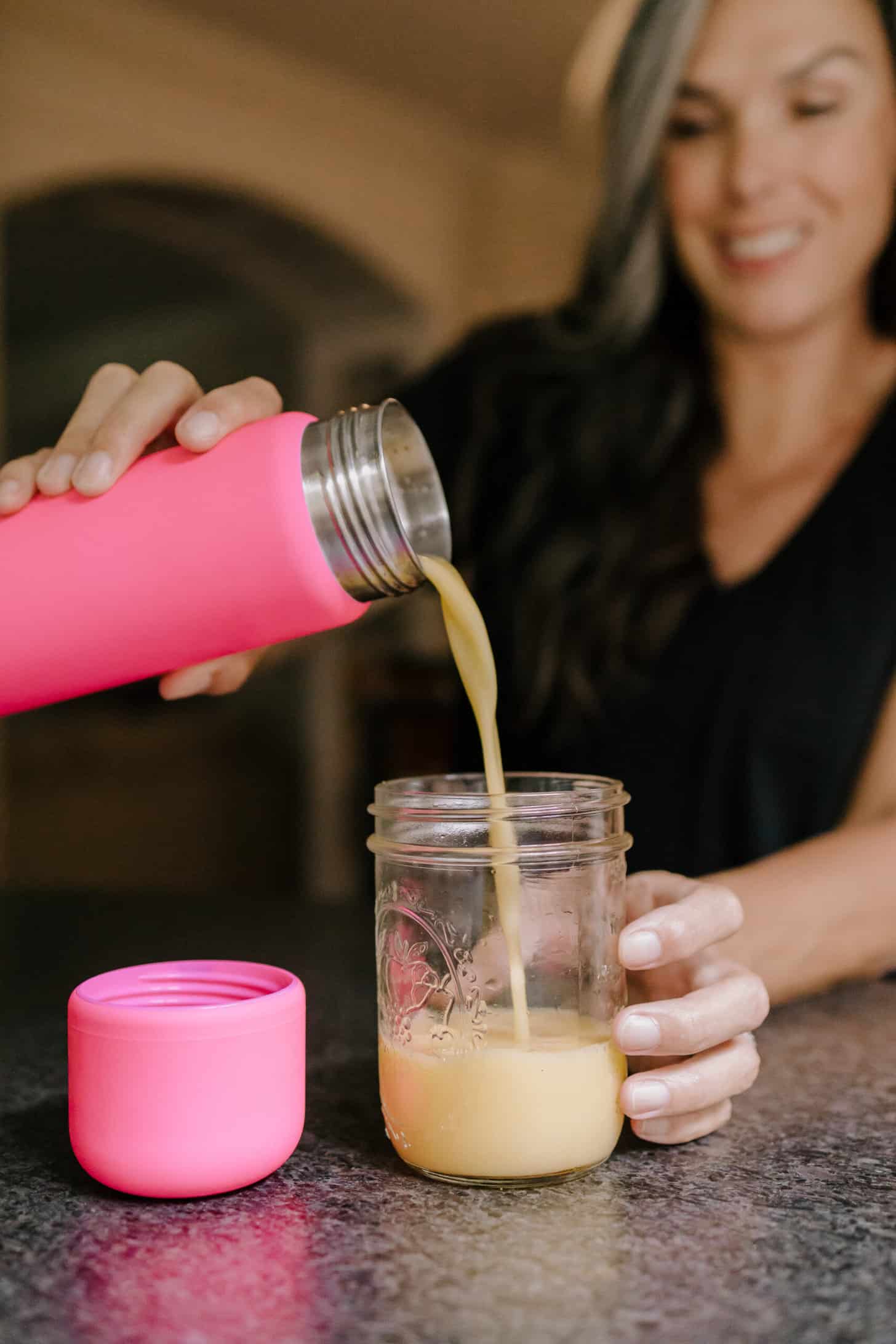 a woman pours a blended drink into a cup