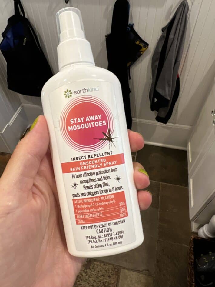 a bottle of earthkind stay away mosquitoes spray is held in a hand
