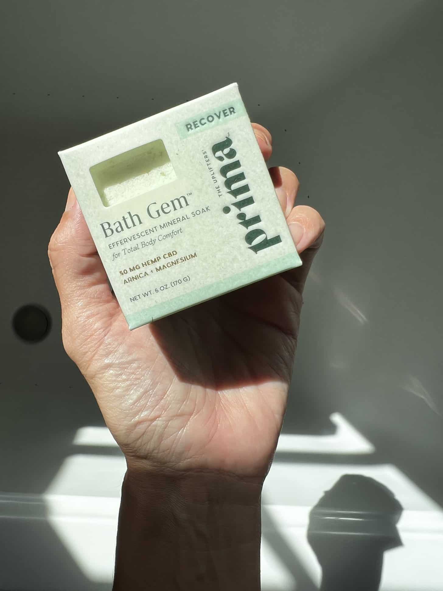 a hand holding up a box of Prima's Bath Gem Recover