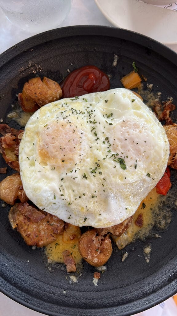 A fried egg on top of sausage and veggies.