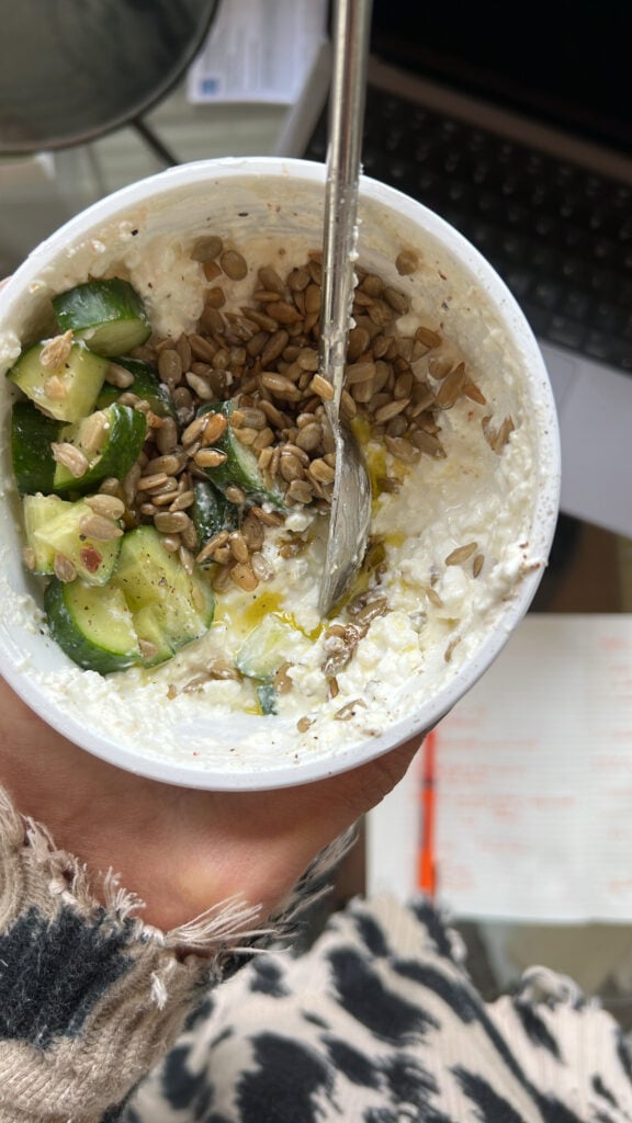 A bowl of cottage cheese with cucumbers and seeds.