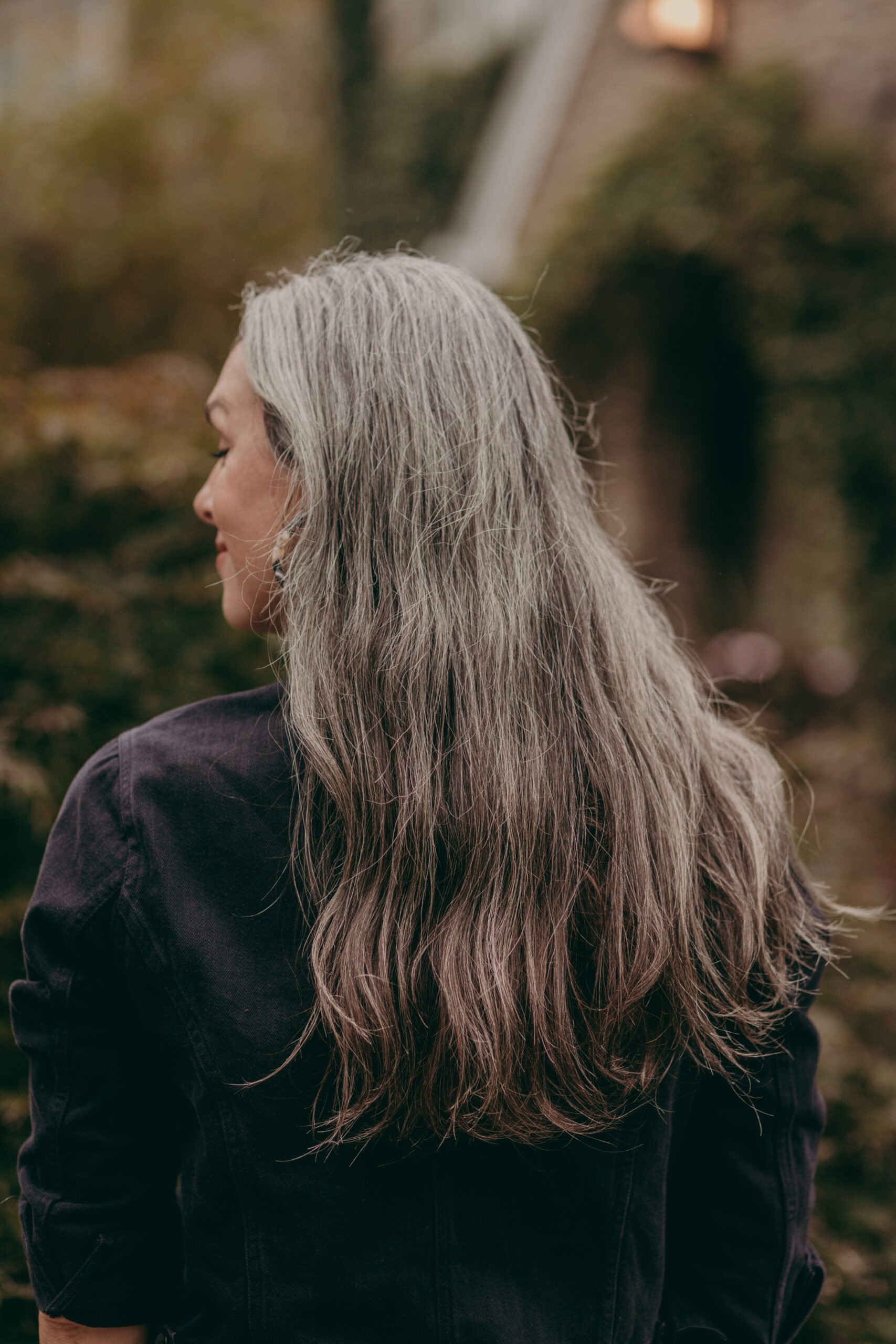 The backside of a woman with long wavy gray hair's head.
