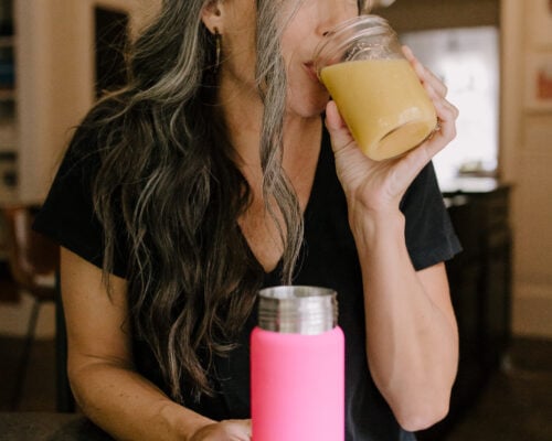 A woman looks off to the side while drinking a blended drink.