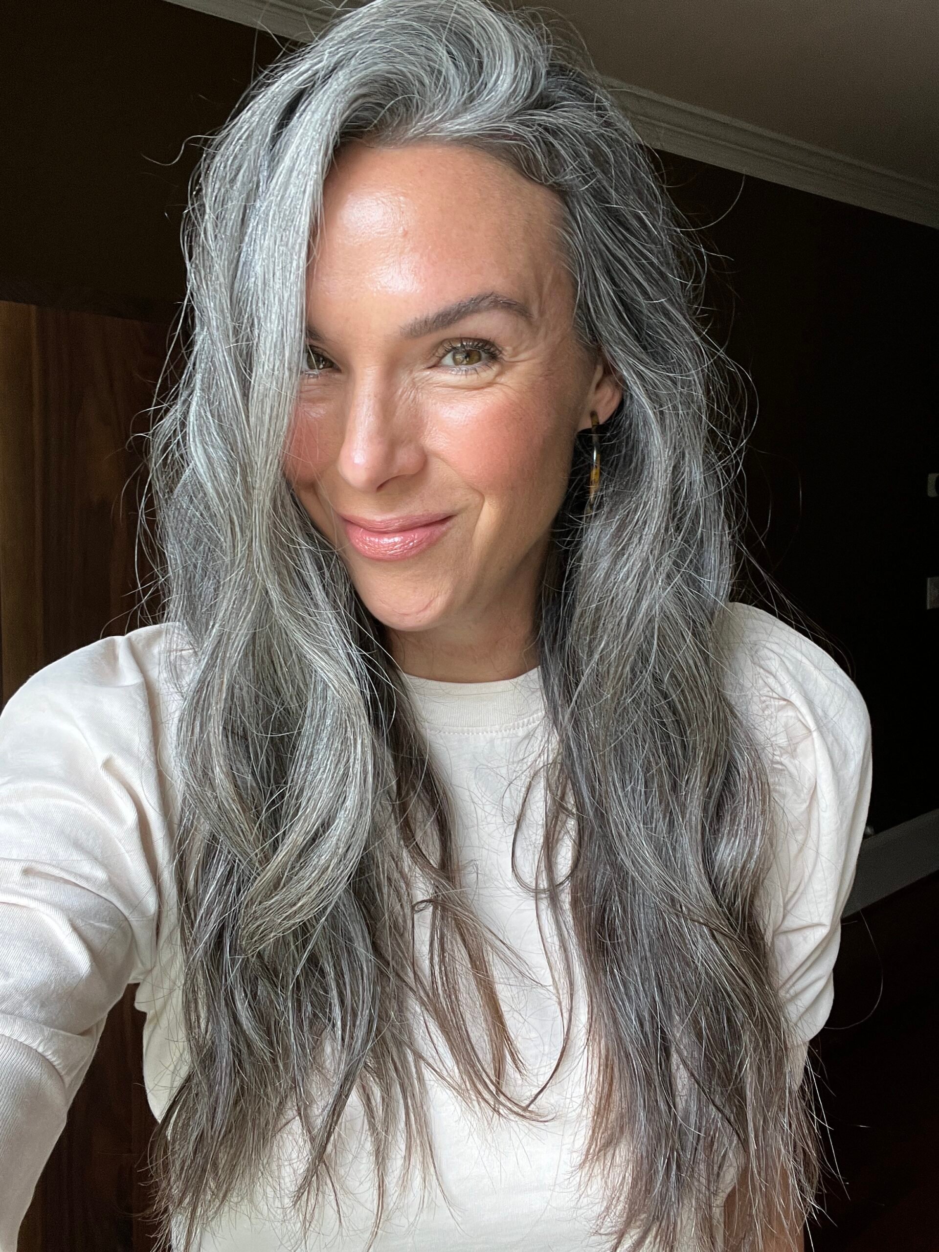 A woman with long wavy gray hair in a white top