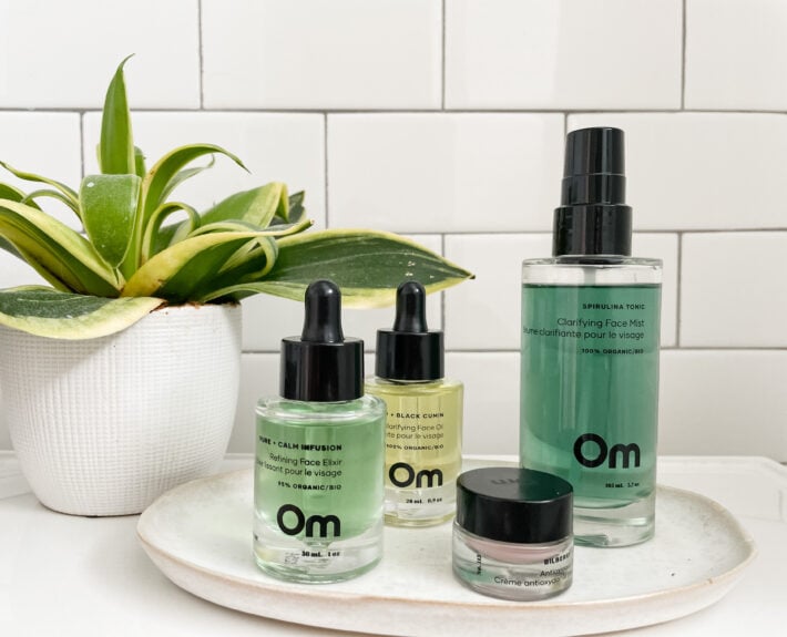 A collection of products from Om sits on a white tray near a plant.