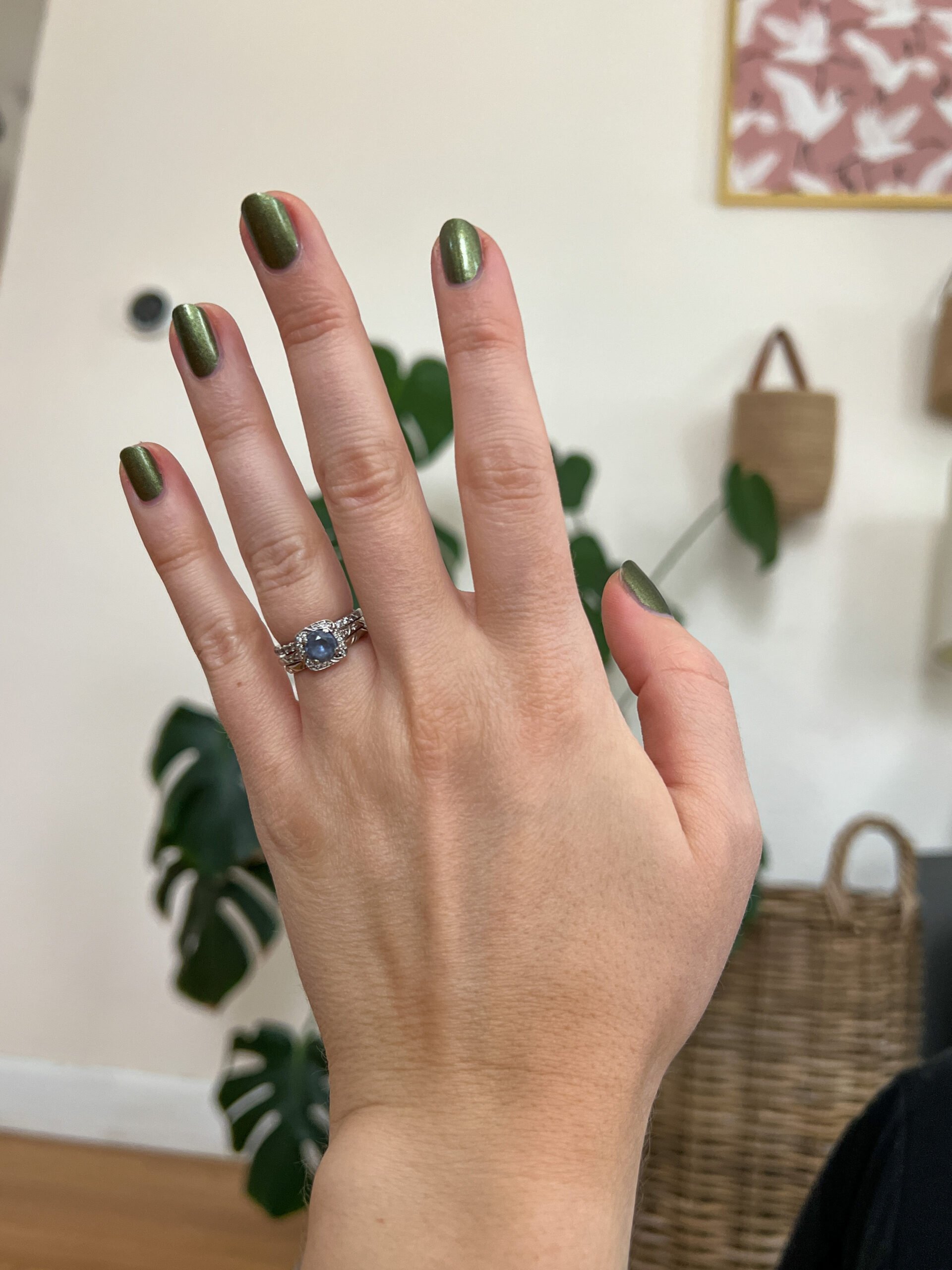 A hand with dark green painted nails. 