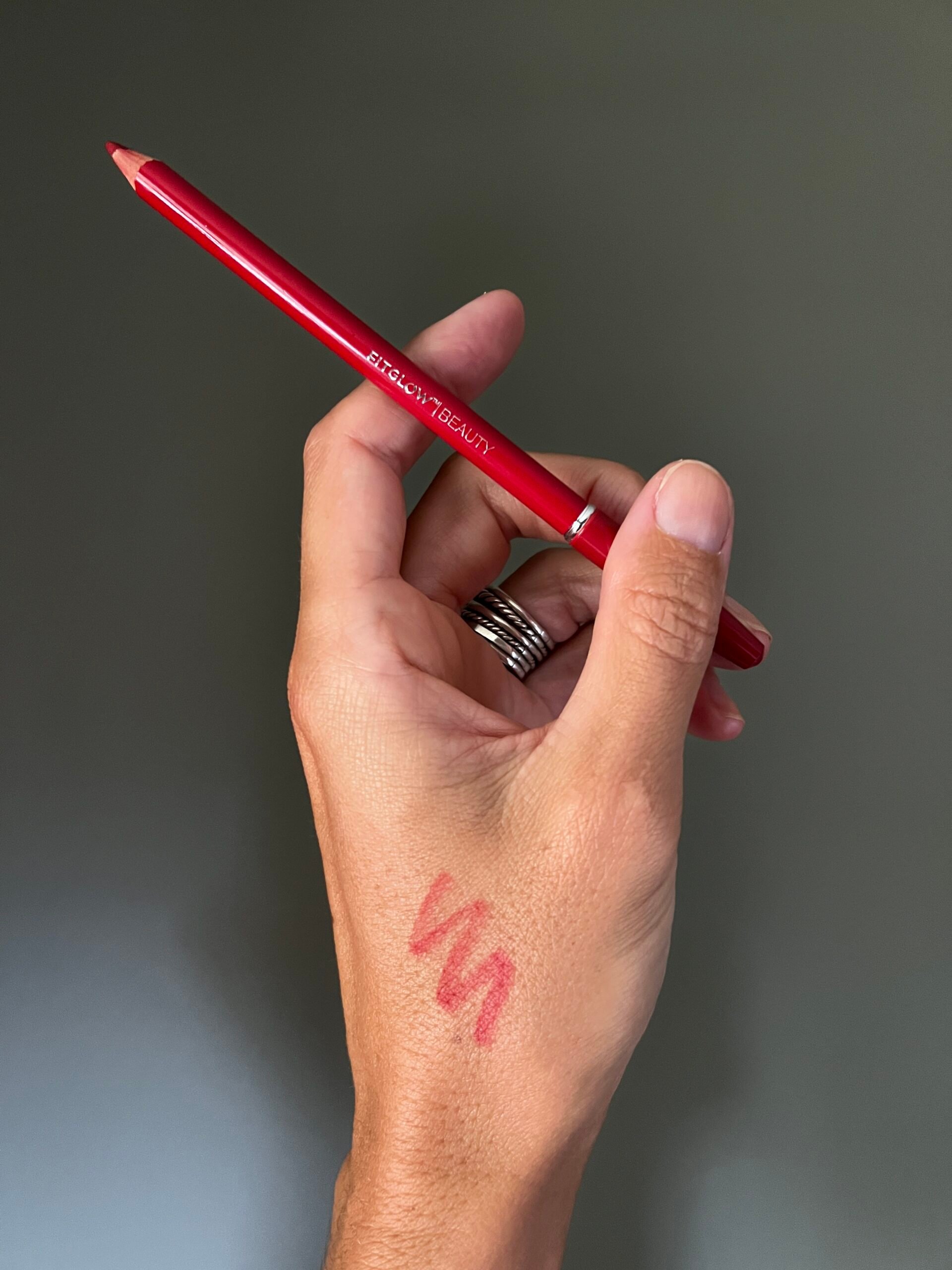 A hand holds up Fitglow Beauty Red Vegan Lip Liner. 