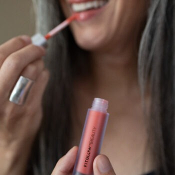 A woman applies Fitglow Lip Serum to her lips.