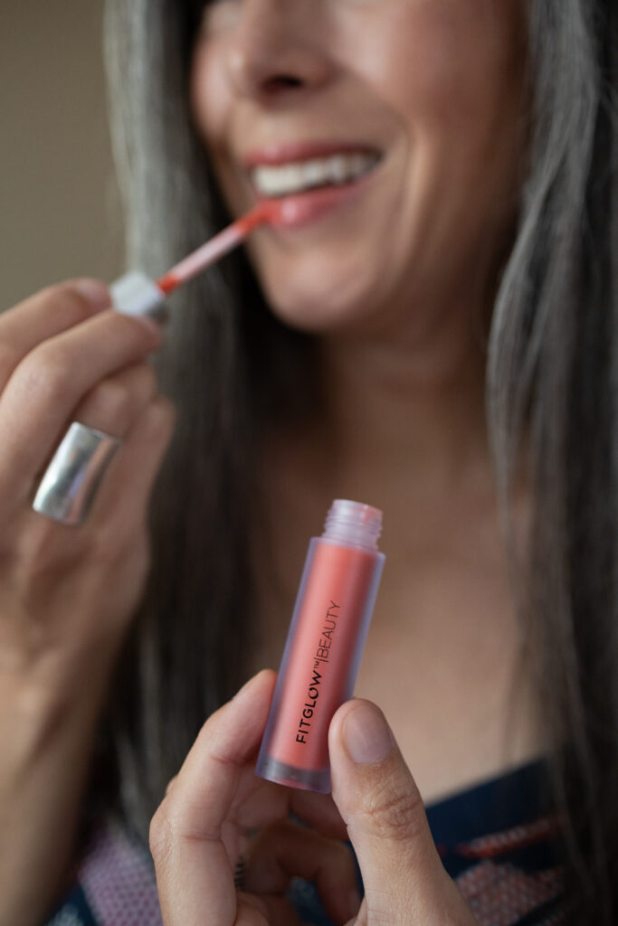 A woman applies Fitglow Lip Serum to her lips.