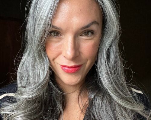 A woman with long gray hair and red lipstick
