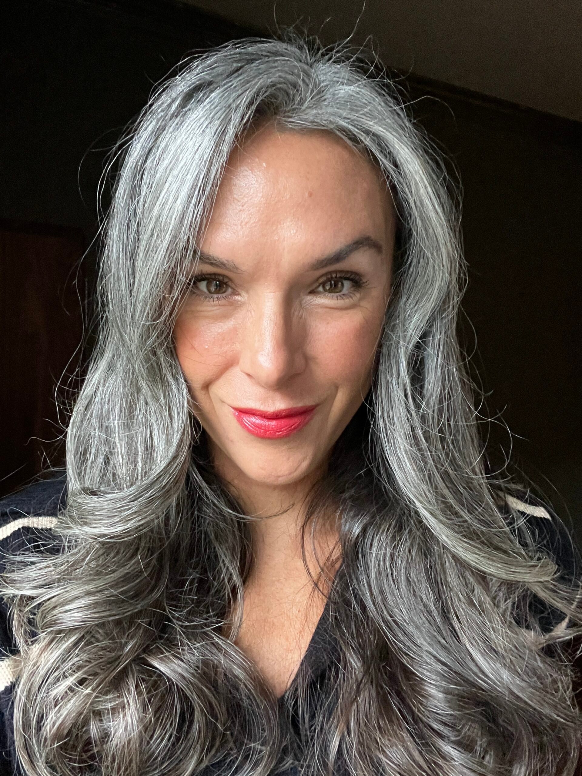 A woman with long gray hair and red lipstick