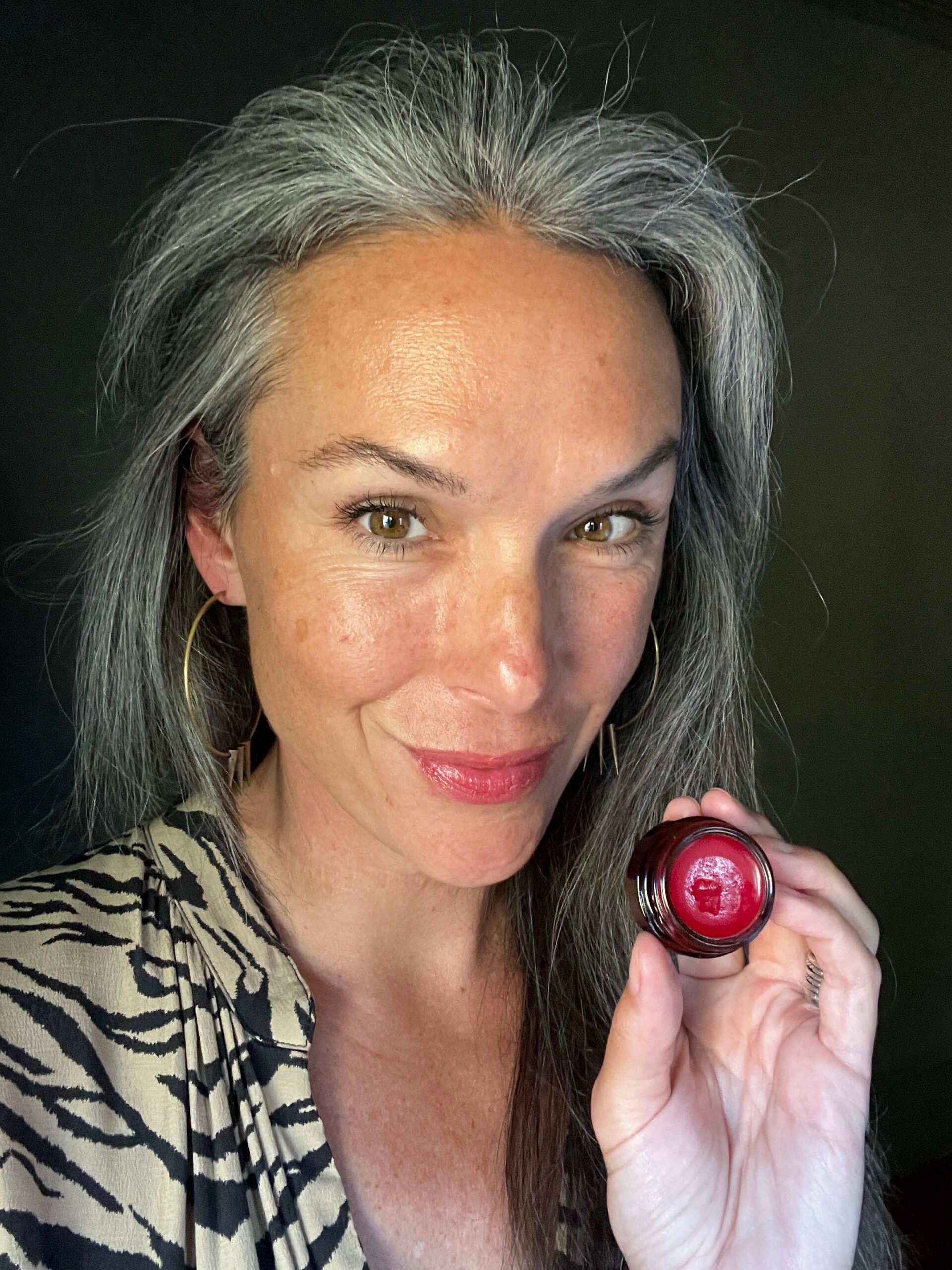 A woman's face while she wears True Botanicals Moisture Lock Glossy Lip Balm in Love. 