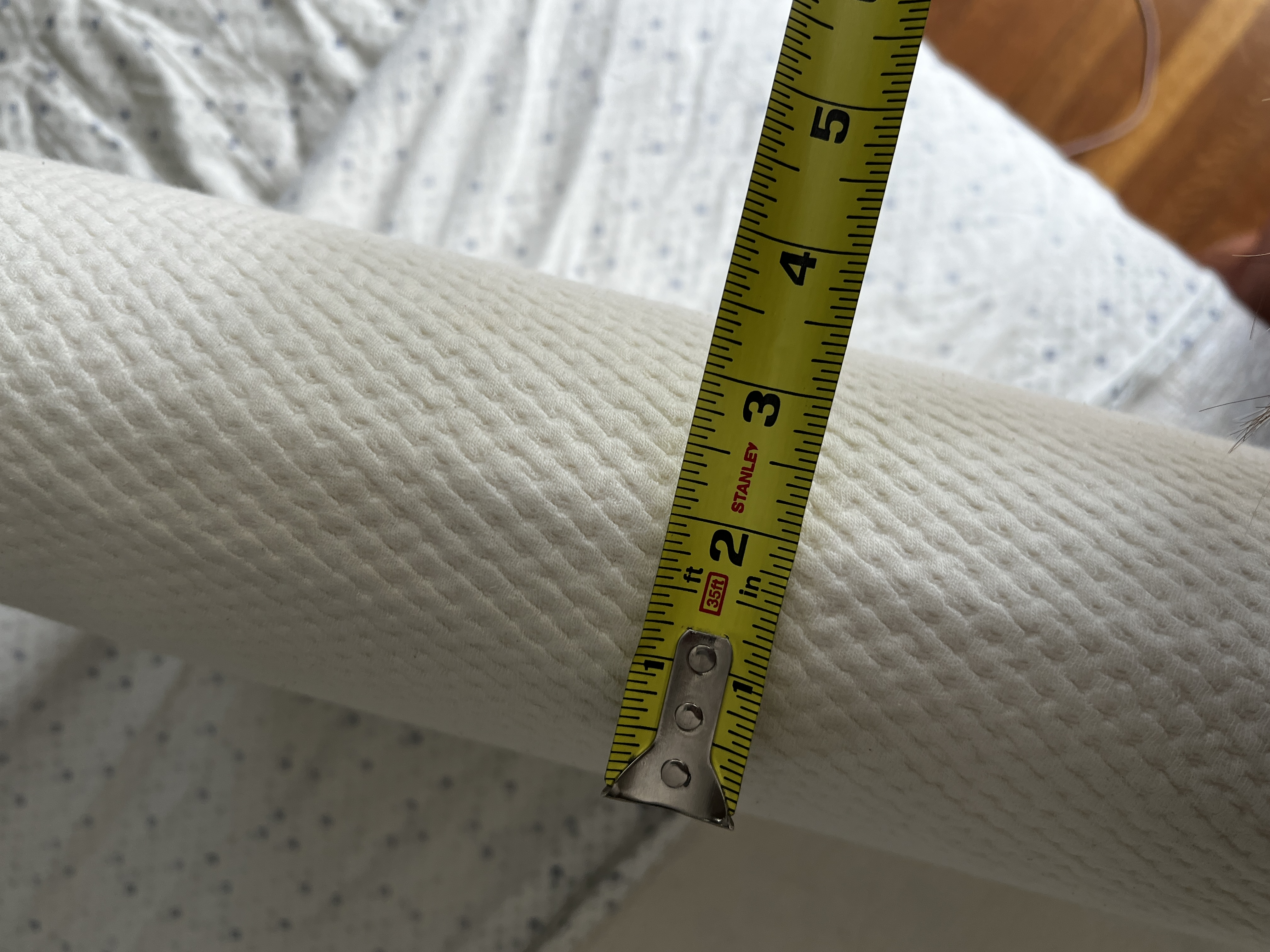 a tape measurers shows the loft of the essentia pillow