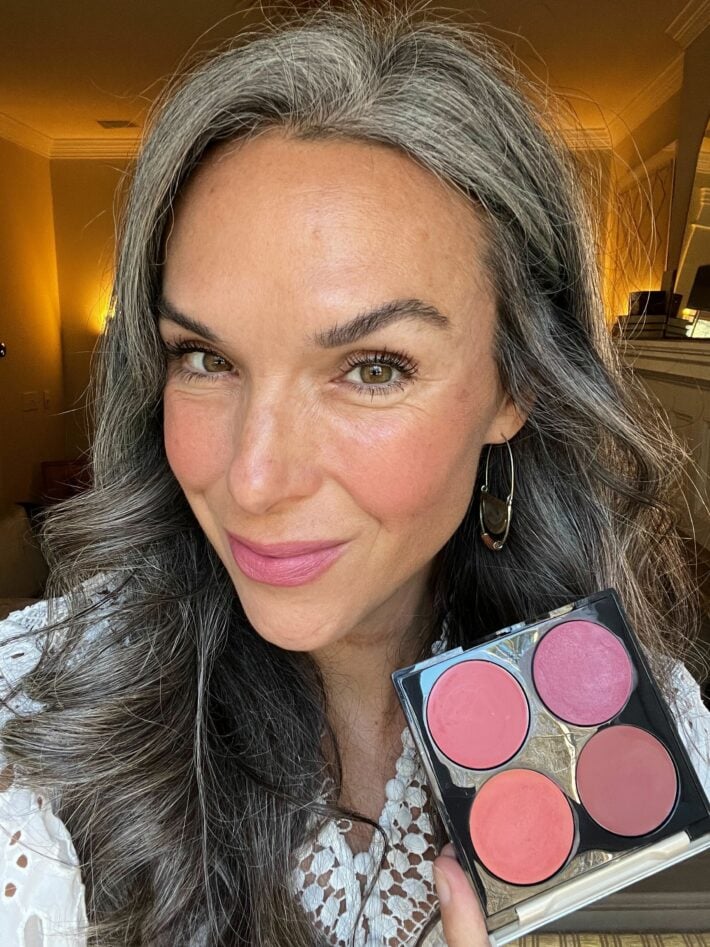 A woman wears FITGLOW BEAUTY palette on her lips and cheeks.