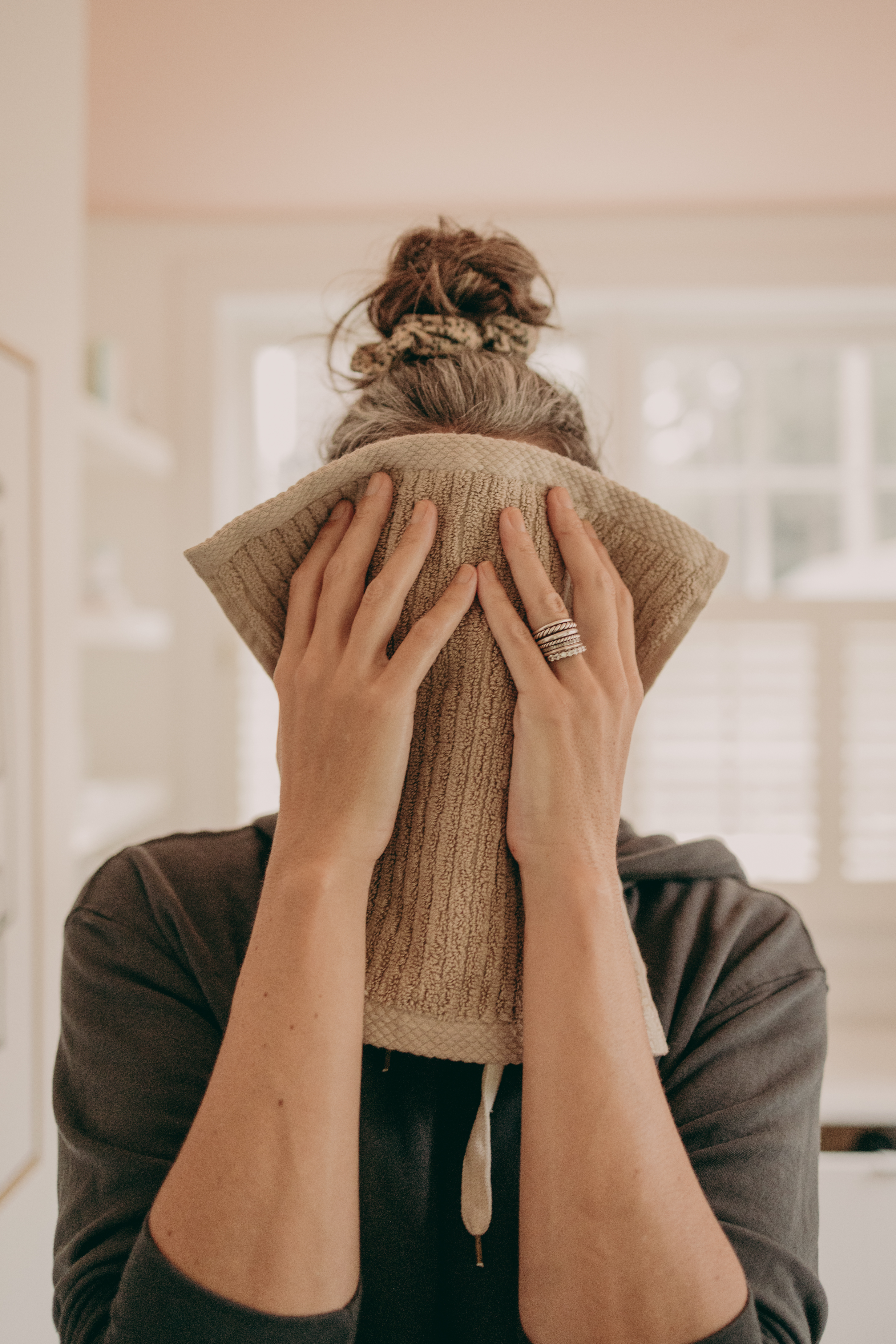 A woman holds up a towel in front of her face.