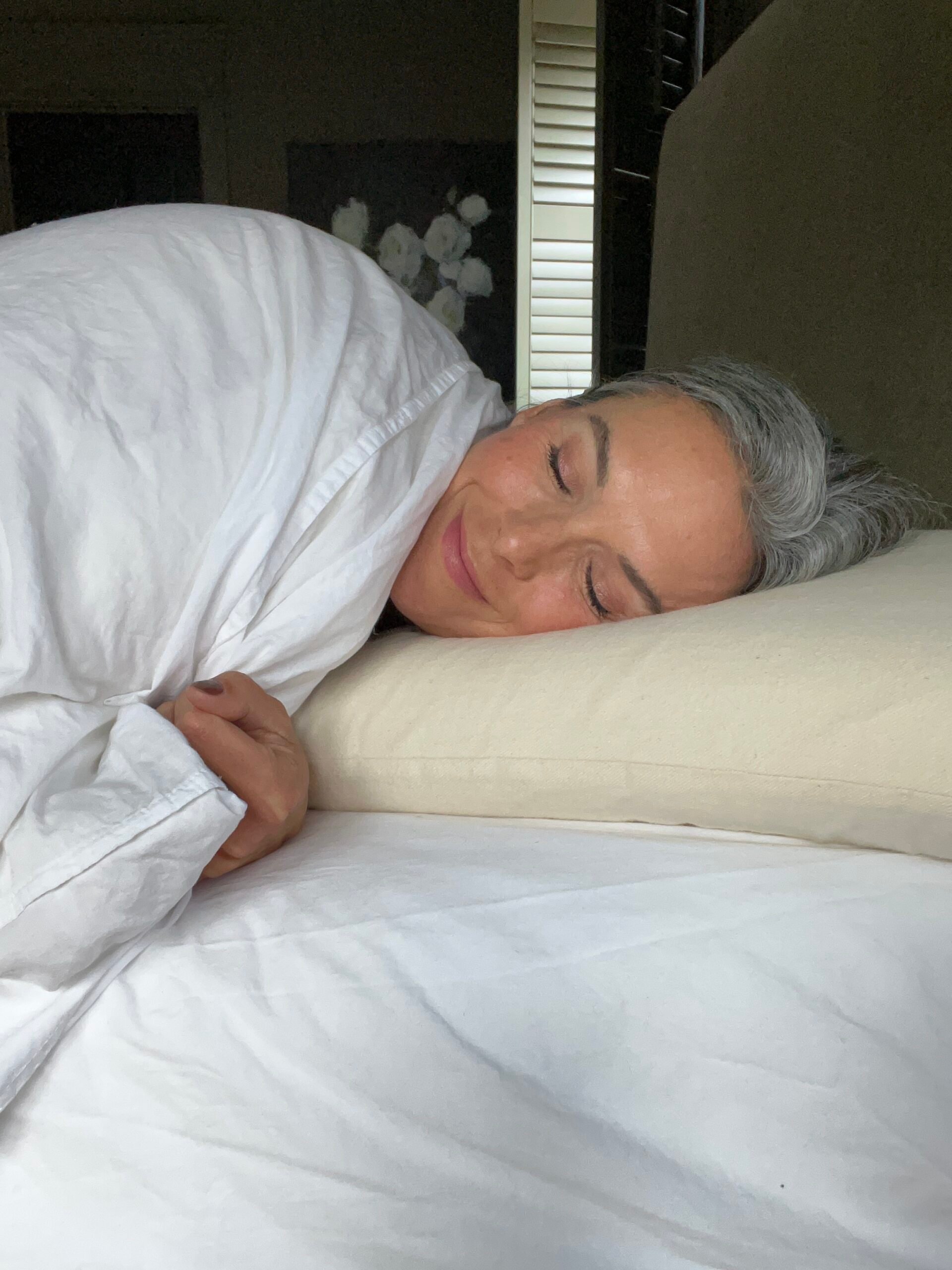 a woman lays on a memory foam pillow in bed