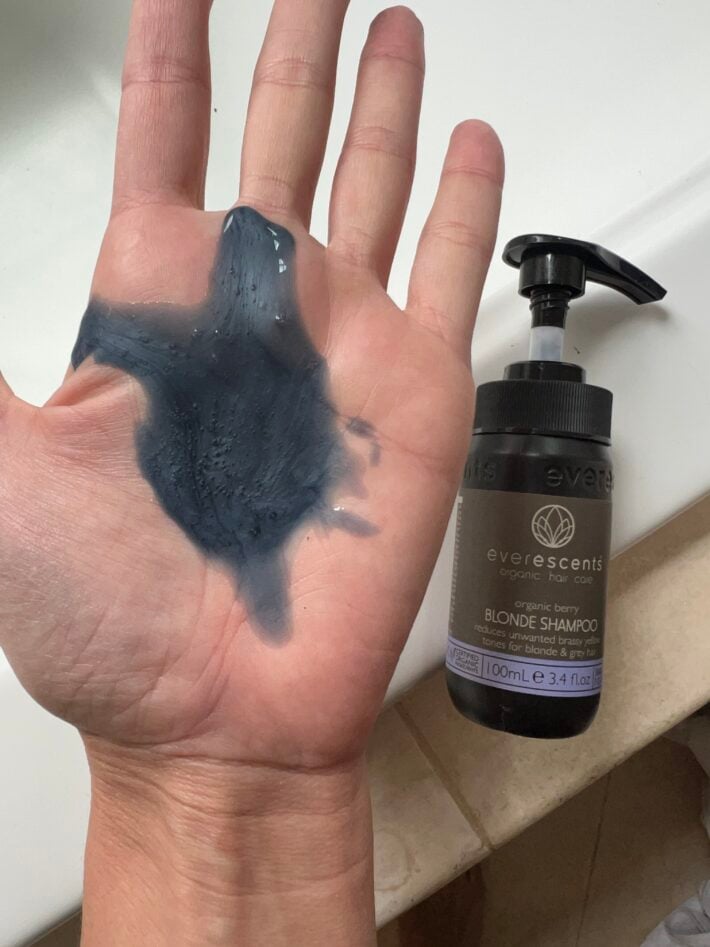 EverEscents Organic Berry Blonde Shampoo on the palm of a hand + bottle.
