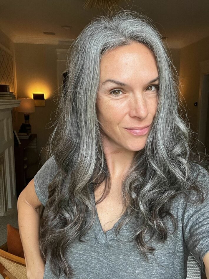 A woman with long wavy gray hair after using Kitsch heatless curls.