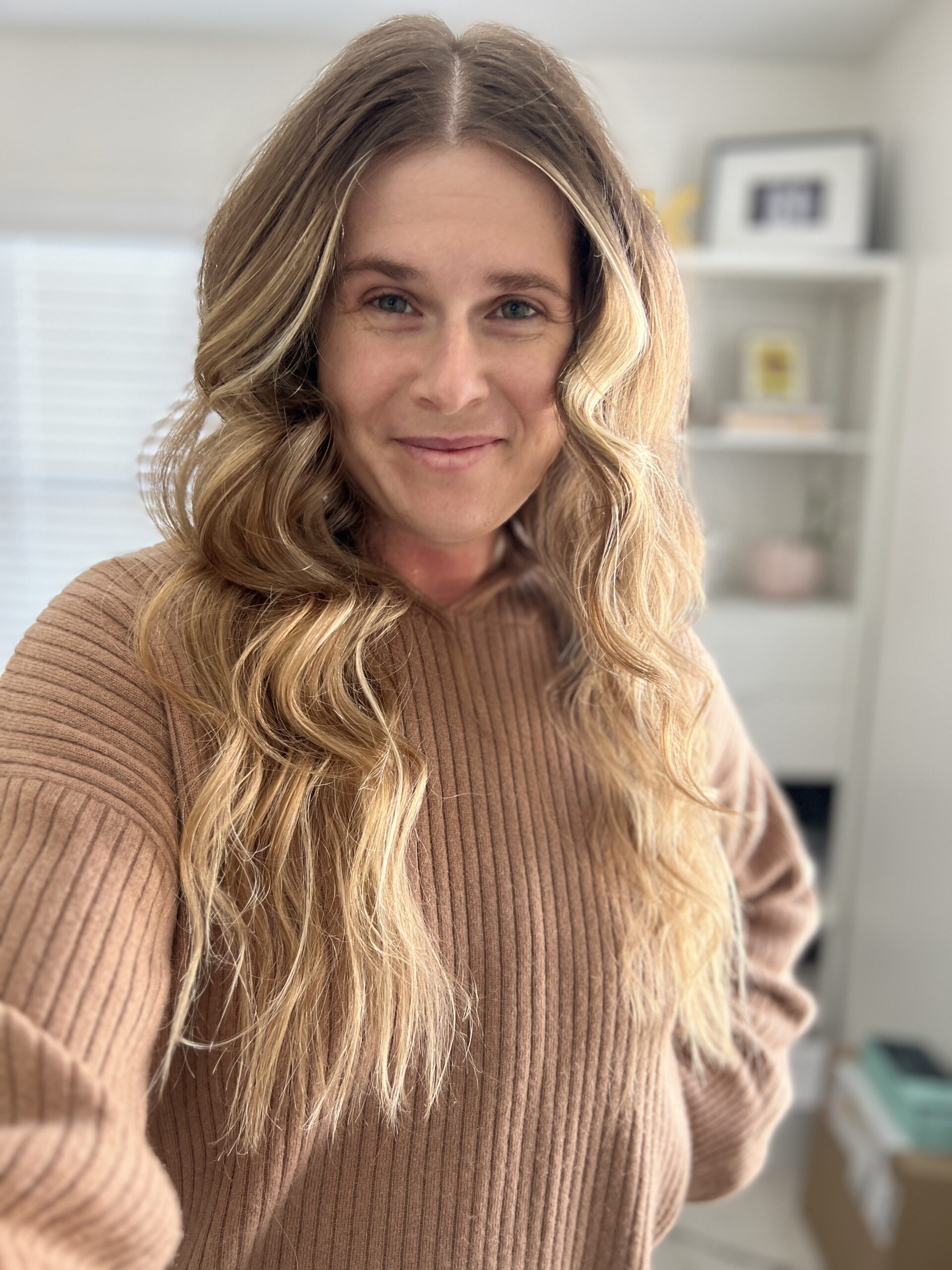 A woman with long wavy blonde hair after using Kitsch heatless curls.