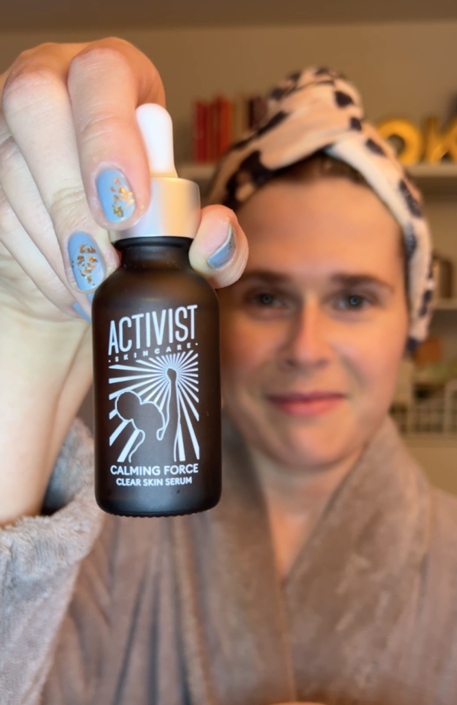 A woman holds up a bottle of Activist Calming Force. 