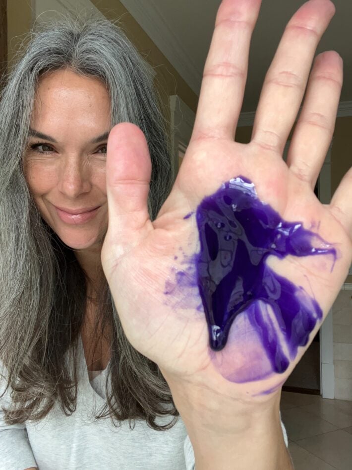 OWAY Silver Steel Hair Bath is a vibrant purple and that is shown on the palm of a woman's hand.