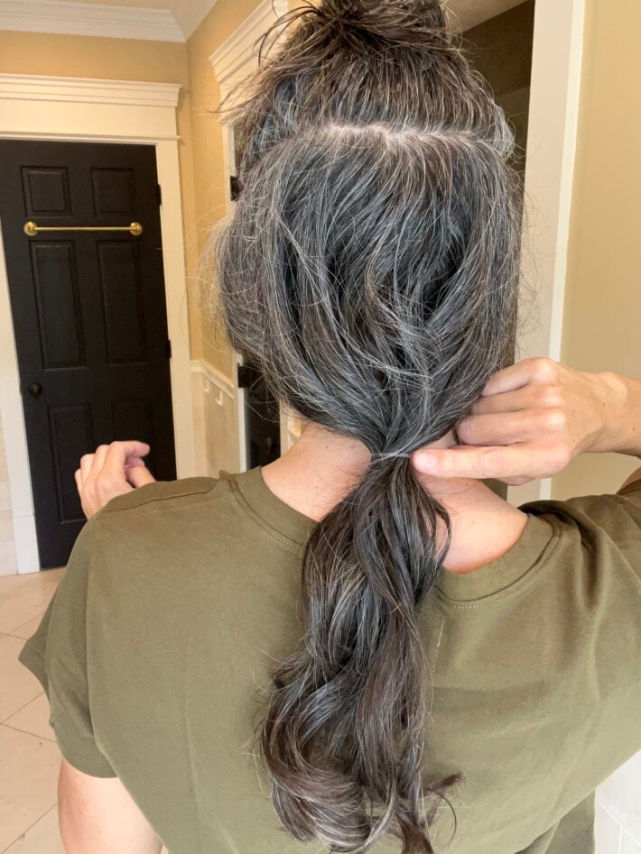 A woman sections the bottom part of her hair into a low ponytail.