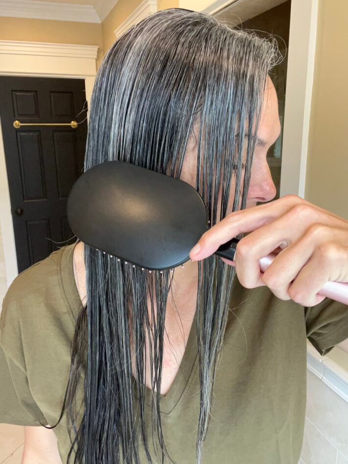 A woman brushing out her long gray hair.