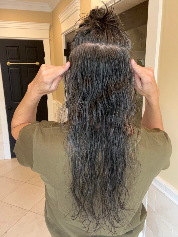 A woman sections off the back part of her hair.