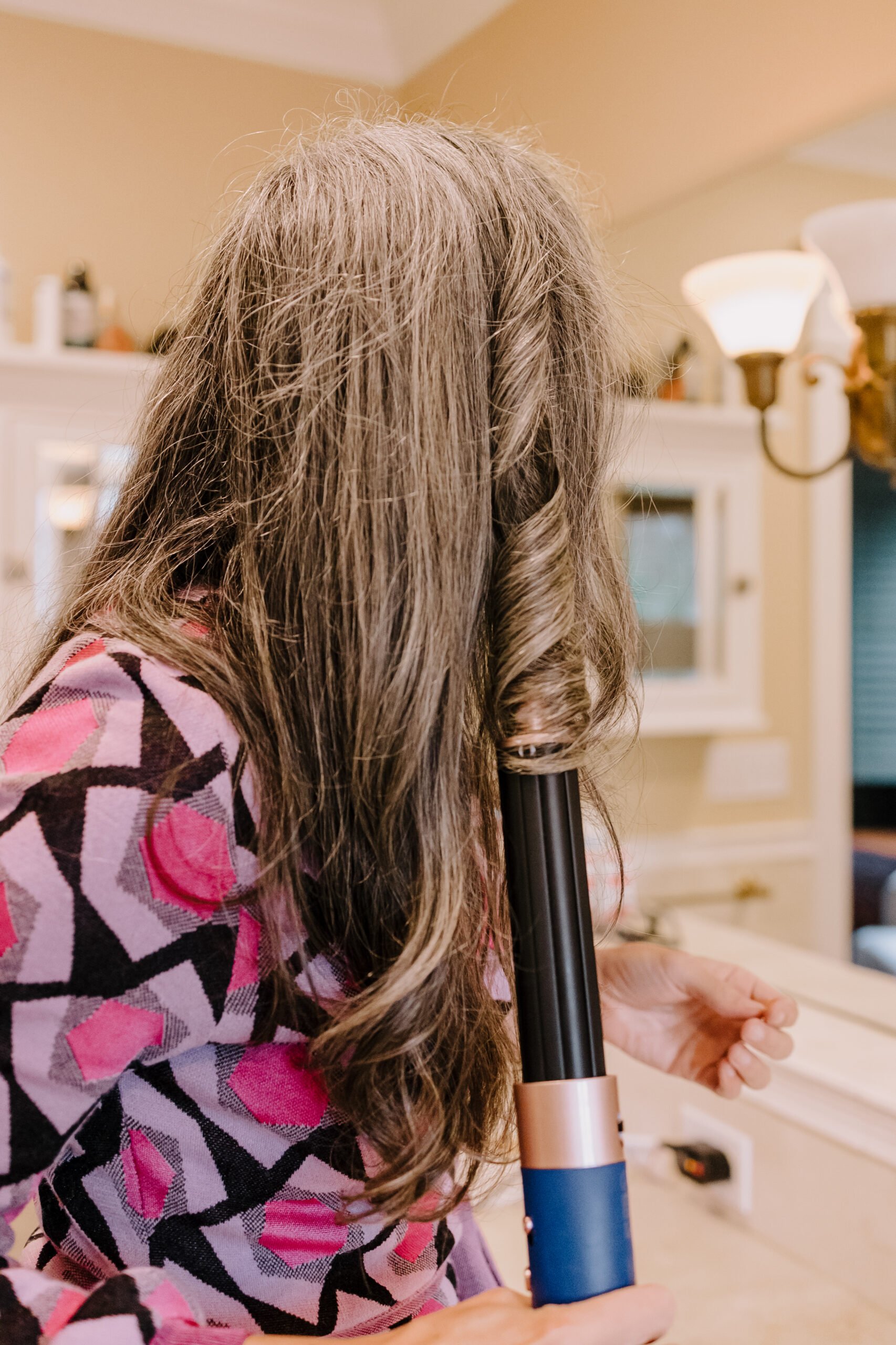 A woman styles her hair with the Dyson Airwrap.