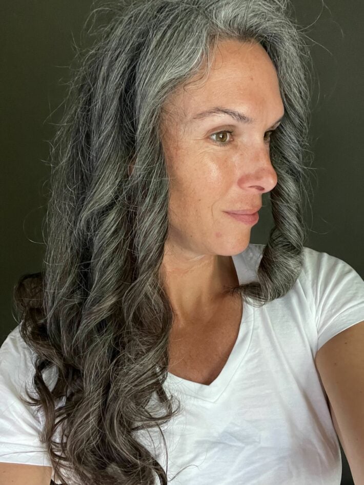 A woman with long curly gray hair after using the Dyson Airwrap 1.2 inch long barrel.