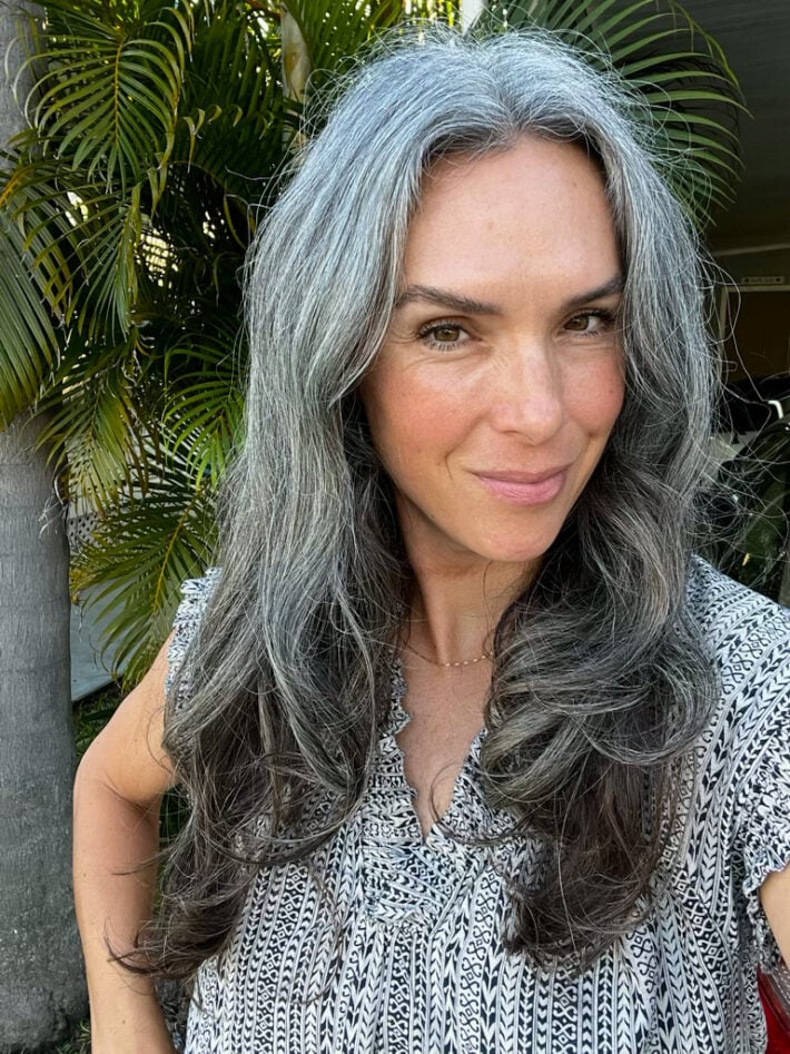 A woman with long gray hair after styling her hair with the Dyson Airwrap.
