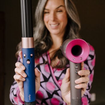 Lisa holds up the Dyson Hair Dryer and Airwrap to compare.