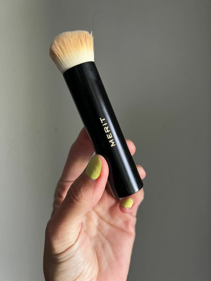 A close up of a hand holding MERIT Beauty's blending brush.