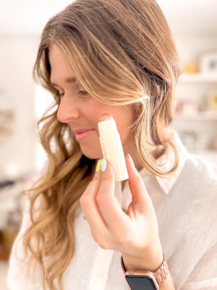 Nicolle holds up MERIT Beauty Day Glow Highlighting Balm.