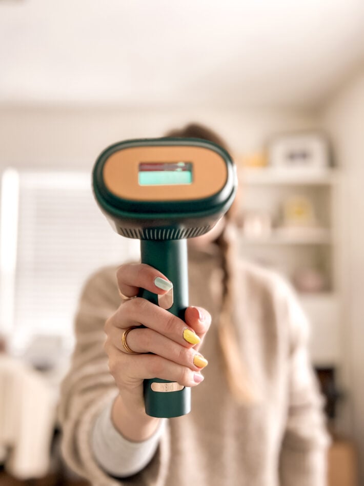 A woman holds up the BoSidin at-Home Hair Removal Device Pro for Women & Men.