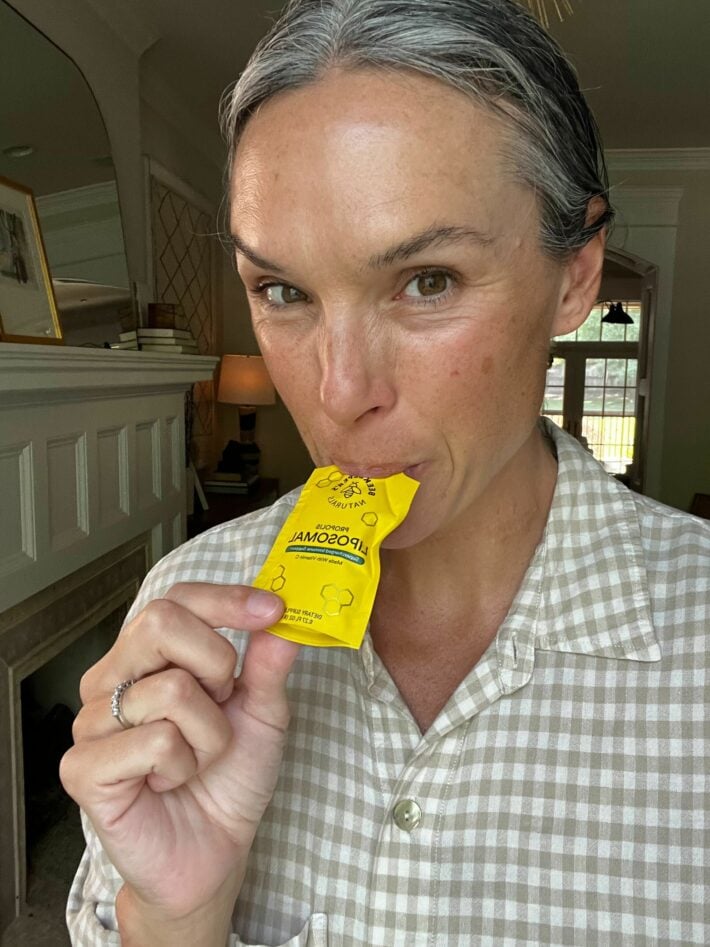A woman sucks on a packet of Beekeeper's Naturals Propolis Liposomal.