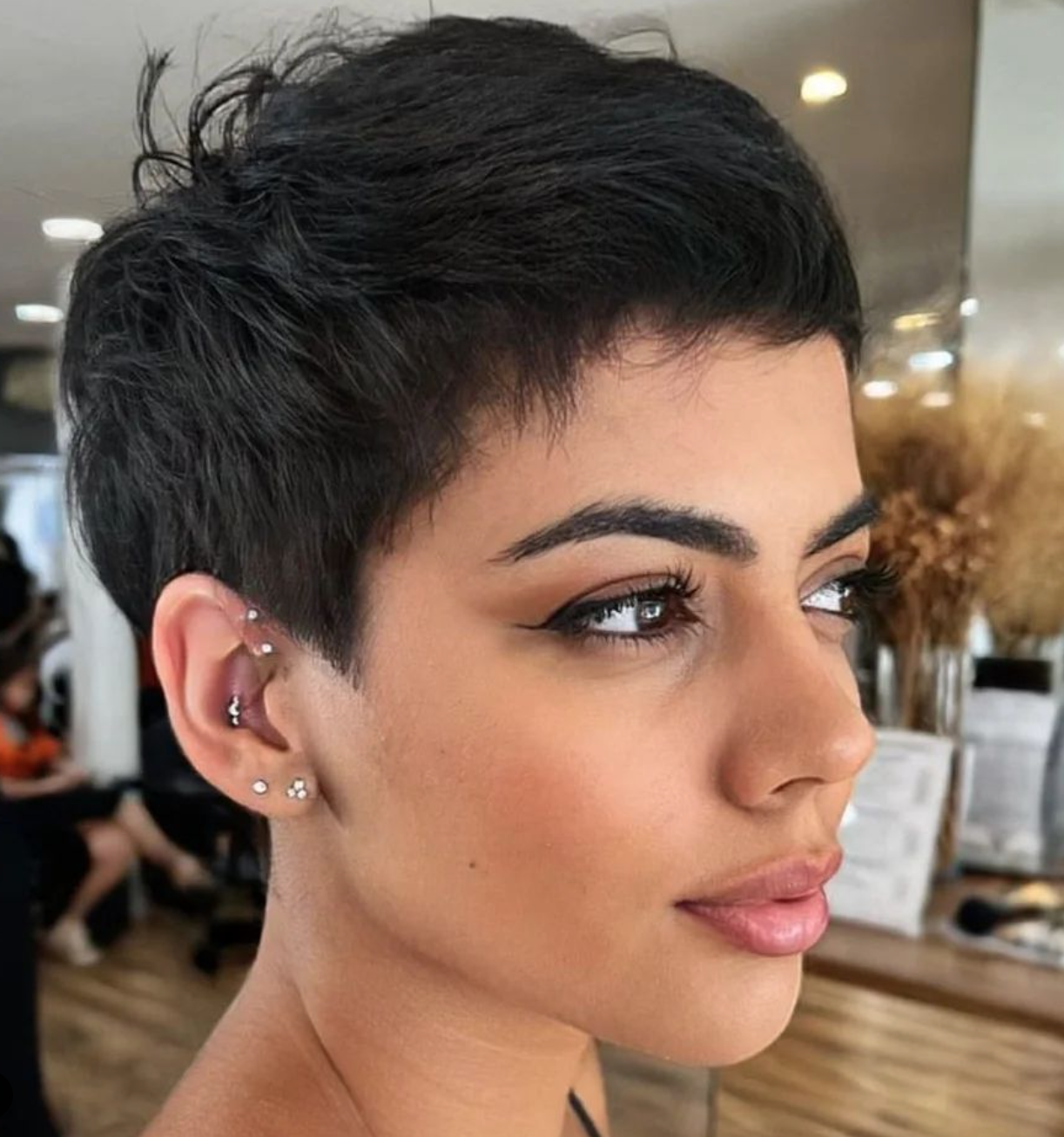 A woman with a black pixie haircut gazes off to the side.