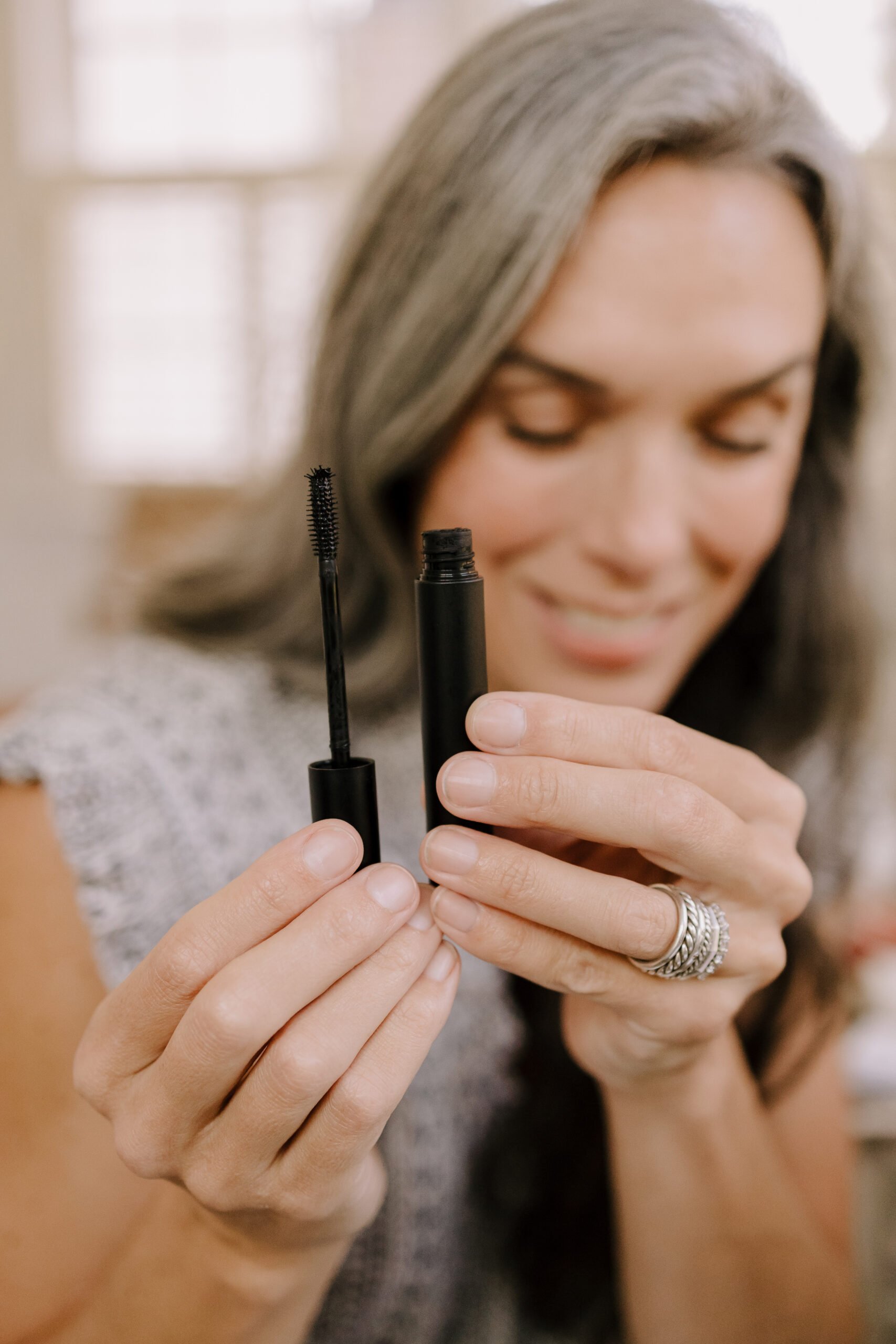 A woman holds up a tube of natural mascara. 