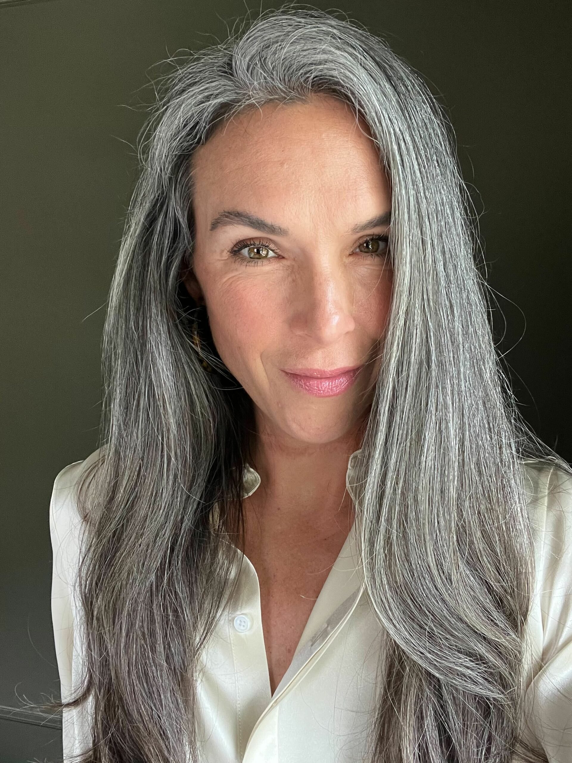 A woman with long gray hair after styling it with the Dyson Airwrap Round brush attachment.