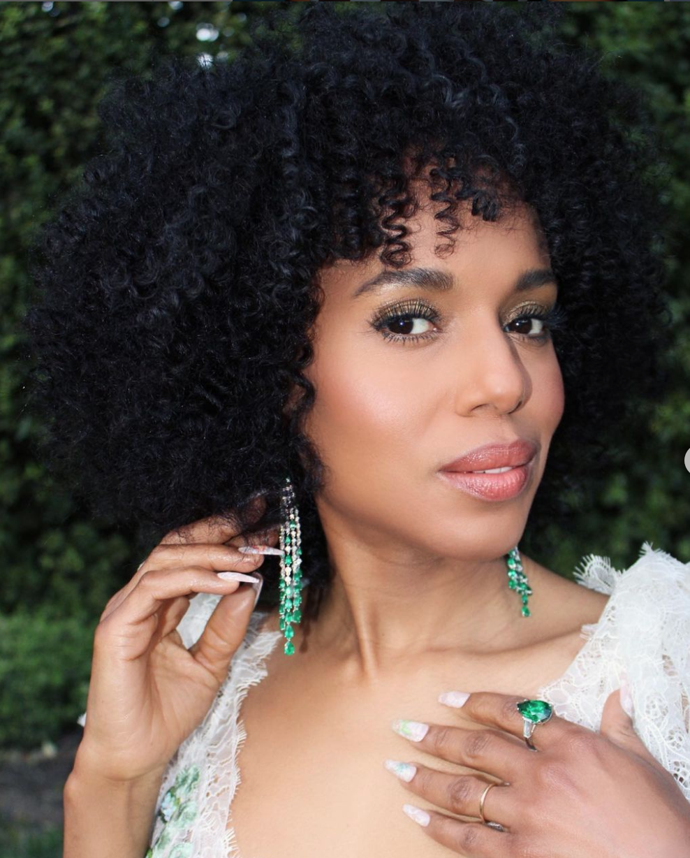 A close up of Kerry Washington with long earrings and fingernails.
